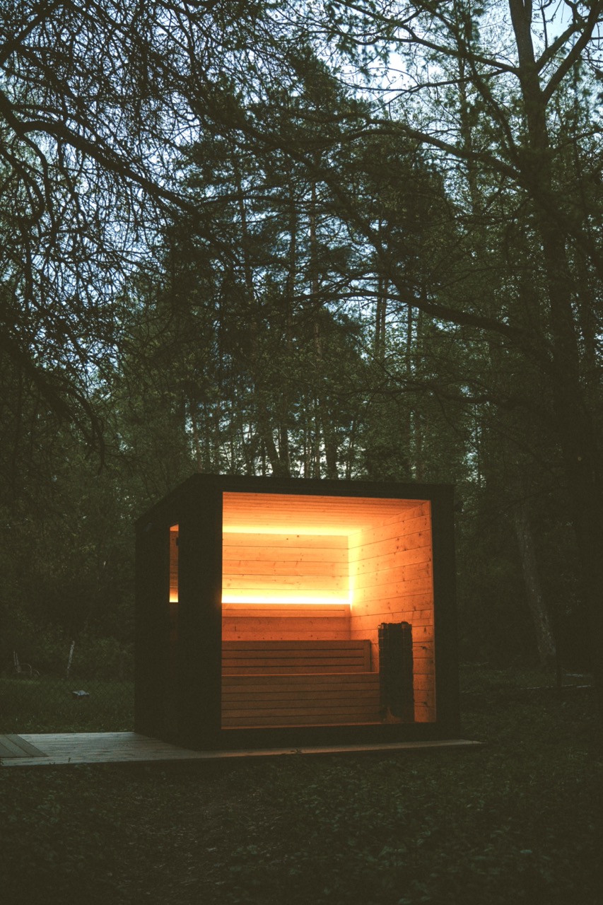 Rozświetlona drewniana sauna pośród drzew w Gniazdowie